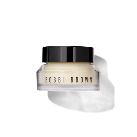 Open jar of Bobbi Brown Vitamin Enriched Face Base showing its rich, creamy texture, with a small swatch on the side.